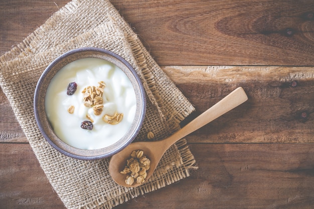 Йогурт украшает зерновые в миске на старом деревянном столе.