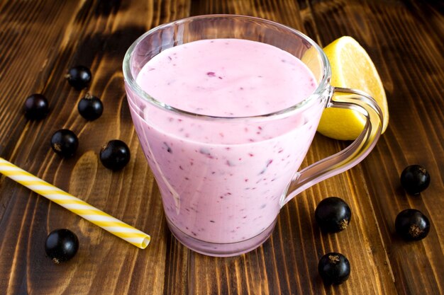 Yogurt smoothies  with  black currant  on the brown  wooden background