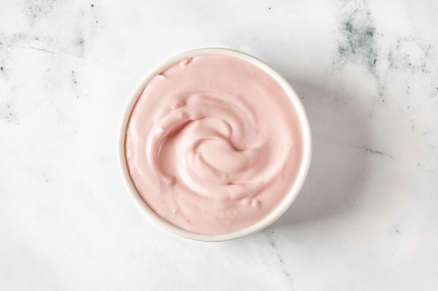 Yogurt with berries in a white round saucer on grey background Texture of white sour cream ice cream