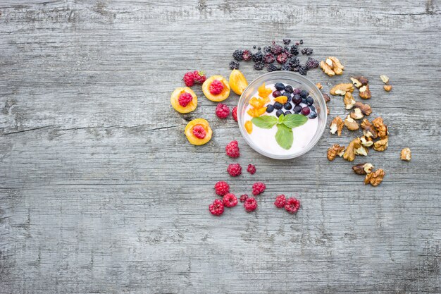 Yogurt con le bacche su fondo di legno, preparato della frutta, concetto per vegetariano