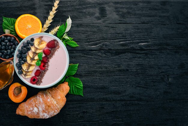 Yogurt with blueberries raspberries and banana In the plate On a wooden background Top view Free space for text