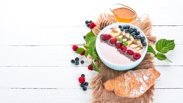 Yogurt with blueberries raspberries and banana In the plate On a wooden background Top view Free space for text