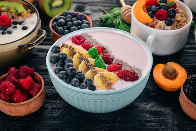 Yogurt with blueberries raspberries and banana In the plate On a wooden background Top view Free space for text