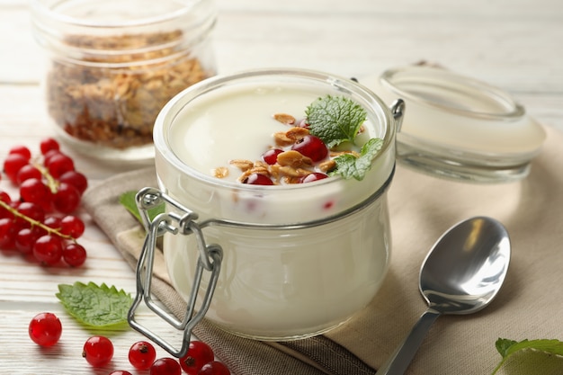 Yogurt con mirtilli rossi, muesli e menta su legno bianco