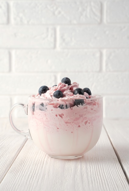 Yogurt with cream and berries on a white table.