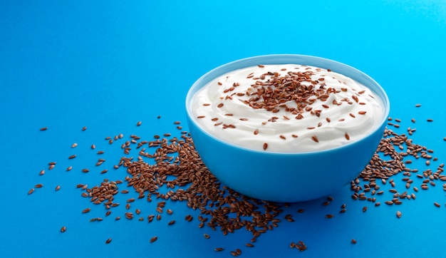 Yogurt with flax seeds isolated on blue background