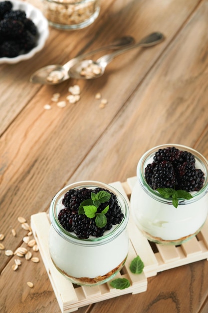 Yogurt with granola blackberry berry fruits and muesli served in glass jar on wooden background Healthy breakfast concept Healthy food for breakfast top view