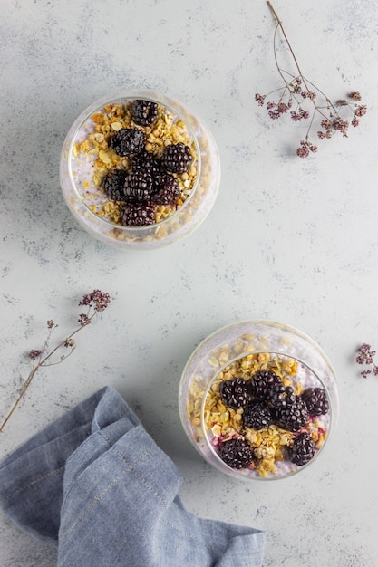 Photo yogurt with granola, chia seeds and blackberries on a grey