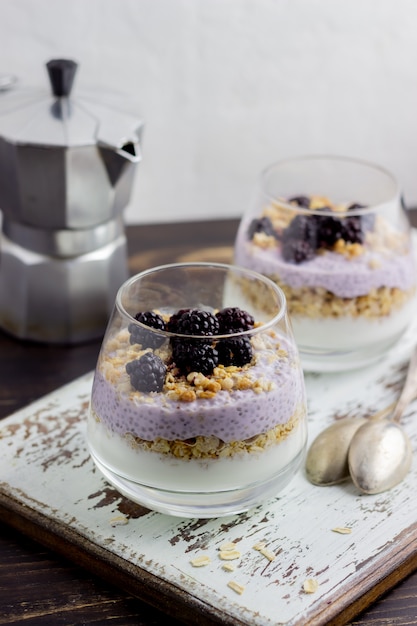 Yogurt with granola, chia seeds and blackberries on a wooden
