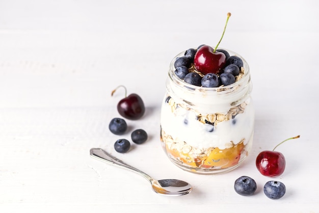 オートミールフルーツとベリーの健康的な食事の朝食素朴な白い木製の背景とヨーグルト