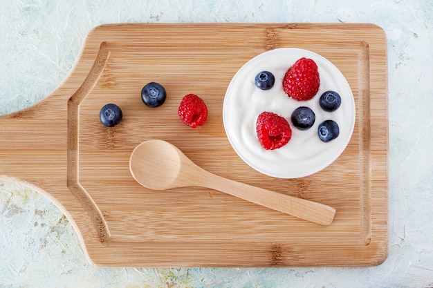 Yogurt with raspberry and blueberries on a wooden board