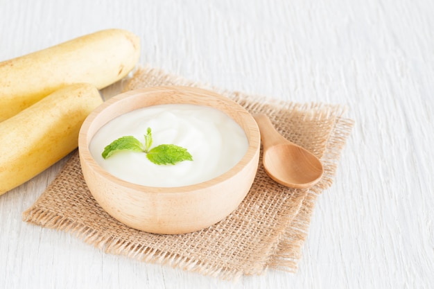 Yogurt in ciotola di legno sulla tavola di legno bianca concetto sano dell'alimento