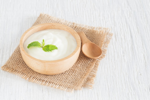 Foto yogurt in ciotola di legno sulla tavola di legno bianca concetto sano dell'alimento