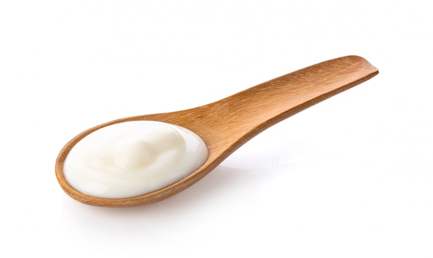 Yogurt in wood spoon on white wall from 