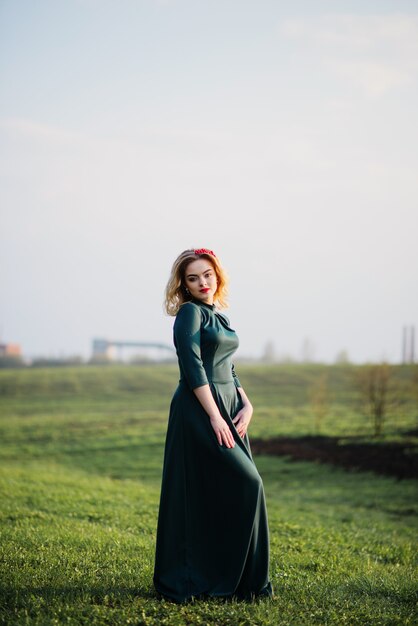 Yong elegant blonde girl at green dress on the garden in spring.