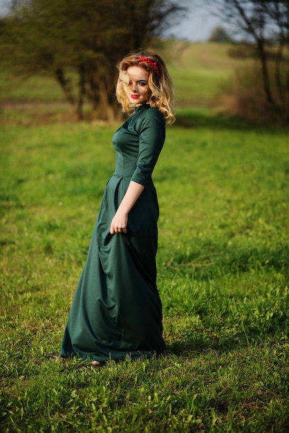 Yong elegantie blonde vrouw op groene jurk op de tuin in het voorjaar