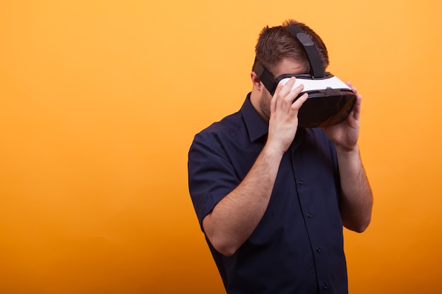 Yong man holding VR with hands over yellow background. Fascinating inovation