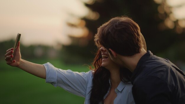 Foto coppia yonug che ha una chat video online sul cellulare al prato primo piano sorridente uomo e donna che hanno conversazione online all'aperto ritratto di giovani che utilizzano lo smartphone per la videochiamata nel parco