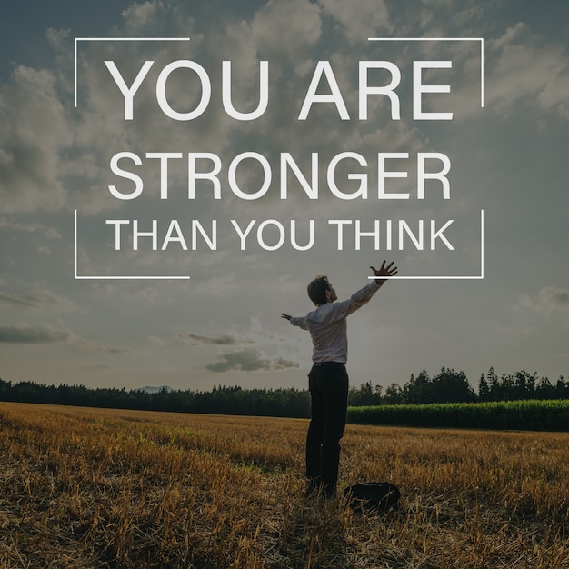 Photo you are stronger than you think sign over a businessman standing in nature with his arms spread widely under evening sky.