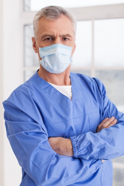 You can trust me! Portrait of senior grey hair doctor in surgical mask looking at camera