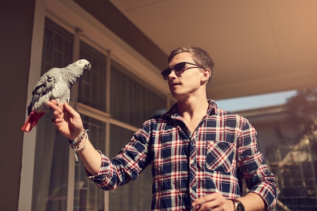 You cant tame the truly free Shot of a young man and an African Gray perched on his hand