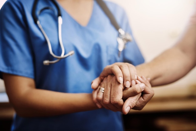 Photo you dont have to face your challenges alone cropped shot of an unrecognizable female nurse holding a senior womans hands in comfort