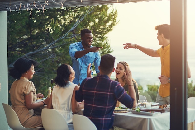 写真 あなたはその正しい仲間を手に入れました屋外の集まりでテーブルの周りで食事と飲み物を一緒に楽しんでいる友人のグループのショット