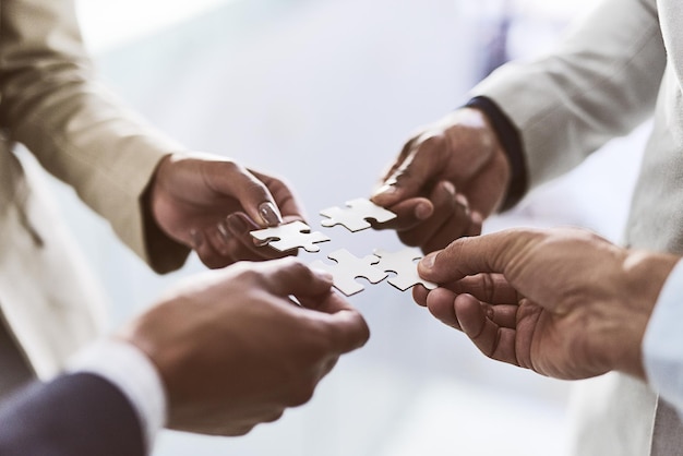 Do you see the bigger picture Closeup shot of a group of unrecognizable businesspeople joining puzzle pieces together in an office