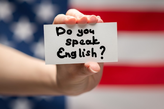 Do you speak English text on a card. American flag surface.