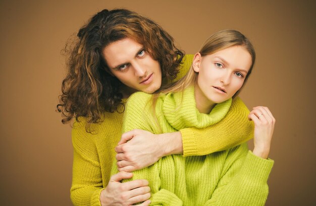 Модная пара Youhg Модная пара позирует для камеры на желтой стене студии