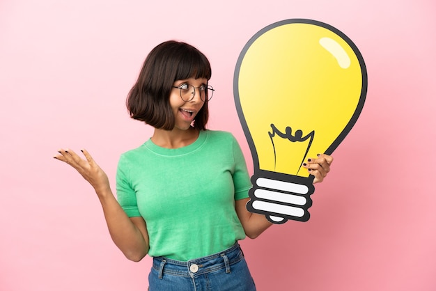 Youing woman holding a bulb icon with surprised expression