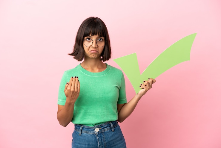 Photo youing woman holding a check icon and doing coming gesture