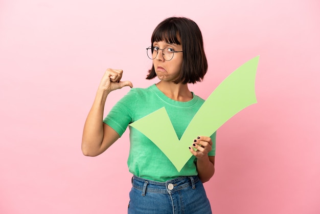 Youing woman holding a check icon with proud gesture