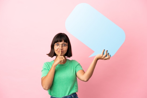 Youing woman holding an empty speech bubble and doing silence gesture