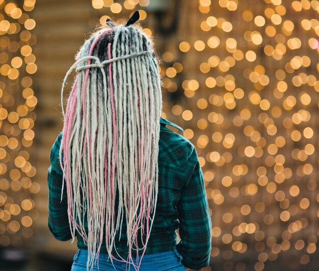 Youn buitengewone vrouw met dreadlocks kapsel en geruite overhemd poseren achteraanzicht