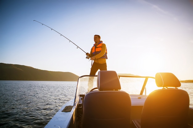 Youn man fishing from a boat