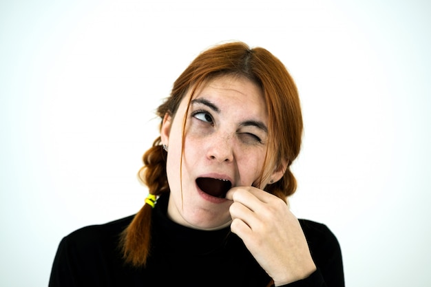 Youn woman with open mouth digging with her fingers for something stuck in teeth after eating.