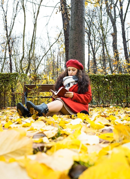 Foto youn donna che scrive note nel parco autunnale