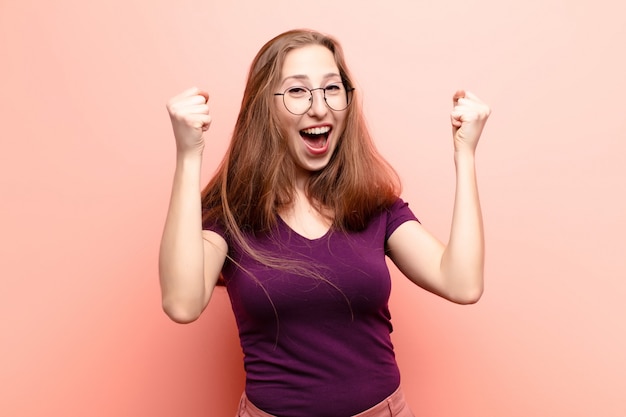 Yound blonde vrouw viert een ongelooflijk succes als een winnaar en ziet er opgewonden en blij uit dat ze dat nemen!