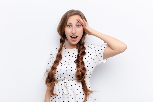 Photo yound blonde woman looking happy, astonished and surprised, smiling and realizing amazing and incredible good news on white wall