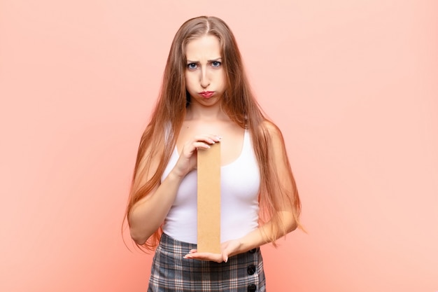 Yound blonde woman sad, depressed, unhappy, holding the letter I of the alphabet to form a word or a sentence