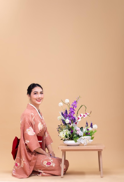 La giovane donna giapponese asiatica degli anni '20 indossa il kimono tradizionale fa una composizione floreale di ikebana