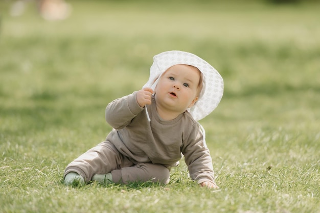 パナマ帽子をかぶった7ヶ月の幼い子供が牧草地で遊んでいます