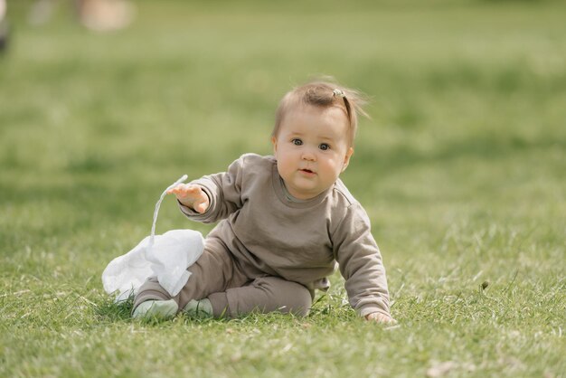 パナマ帽子をかぶった7ヶ月の幼い子供が牧草地で遊んでいます