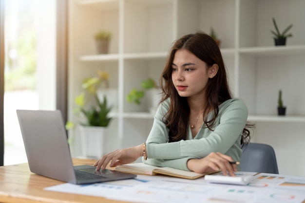 Giovane ragioniere freelance che lavora in ufficio utilizzando il computer portatile con il concetto di calcolatrice finanza aziendale e concetto di debito fiscale contabile