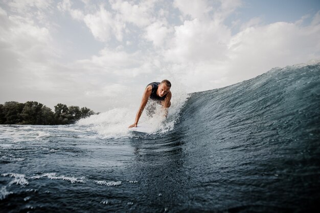 Young active man standing on the one knee on the white wakeboard