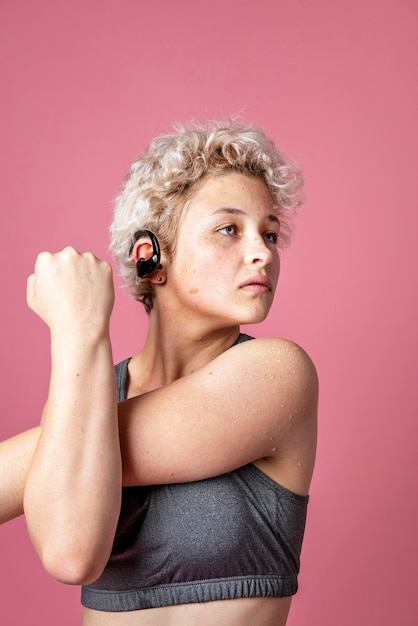 Young active woman wearing a bluetooth headset while stretching