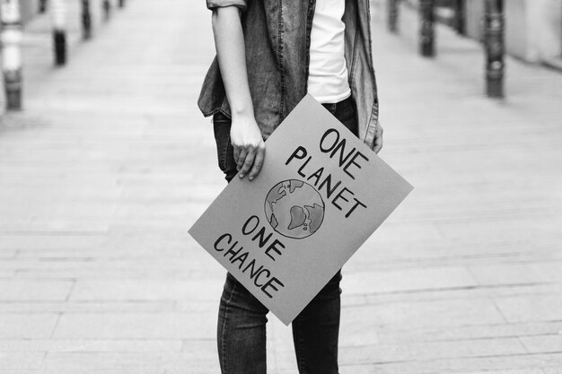 Young activist marching and protesting for climate change\
holding banner ecology concept