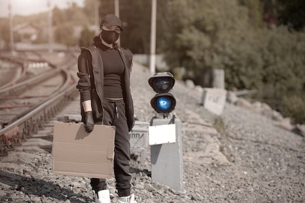 A young activist with a poster in her hand at a railway station, dressed in black clothes