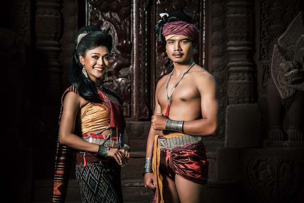 Young Actor and Actress wearing beautiful ancient costumes, in ancient monuments, dramatic style. Perform on legend love popular story, Thai Isan folktale called "Phadaeng and Nang-ai" in acient site